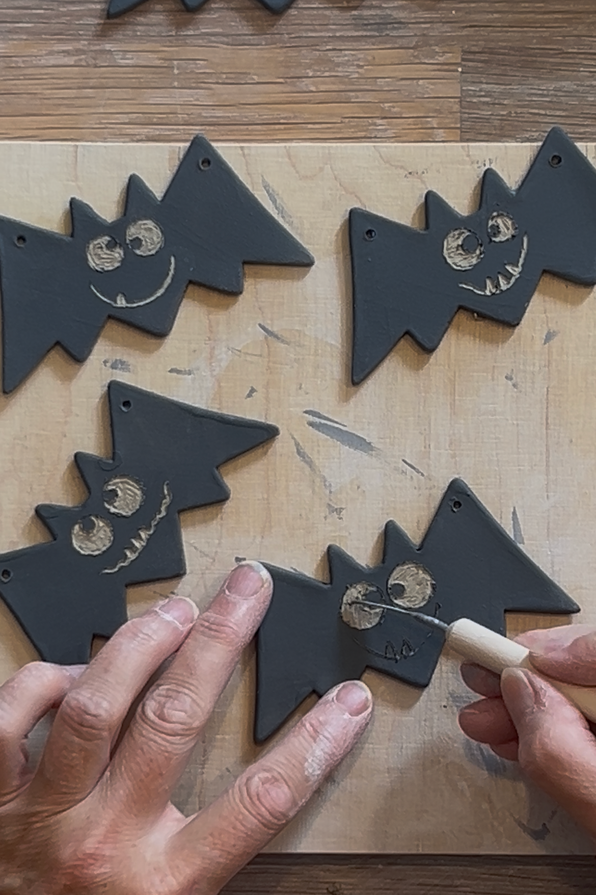 Fledermaus-Motive aus Keramik auf einer Arbeitsunterlage. Kreatives Arbeiten mit einer Ton Ausstechform und einem praktischen Ausstecher fürs Töpfern zum Gestalten von Halloween-Dekoration.